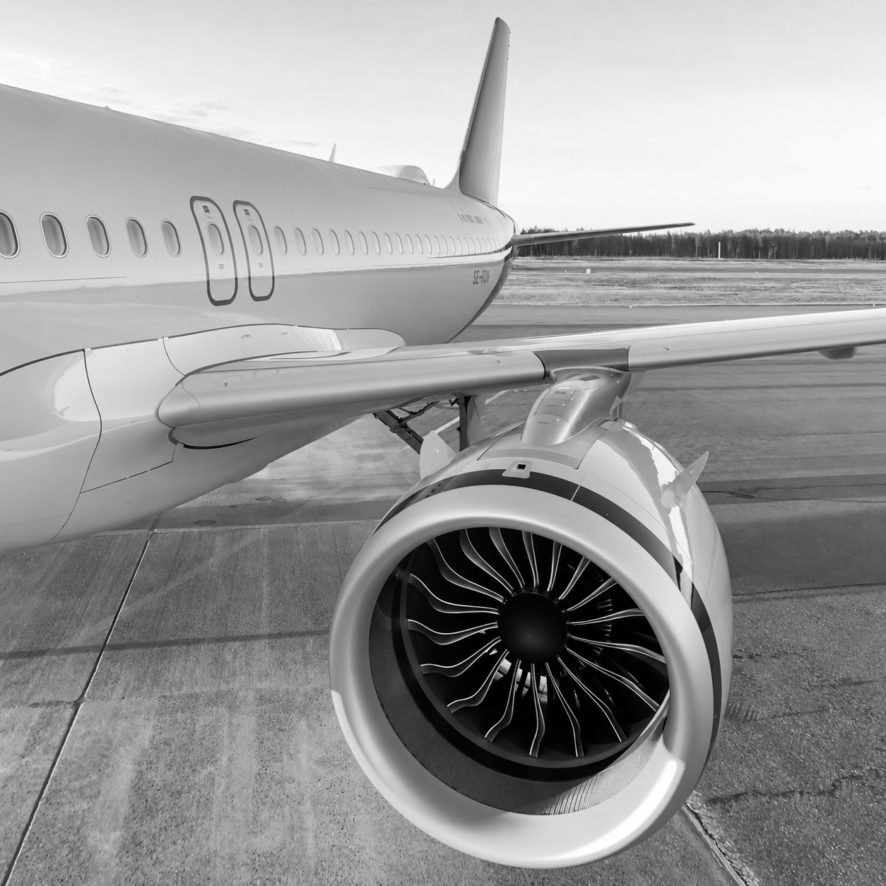 Wider view of an aircraft engine, wing and fuselage on the apron